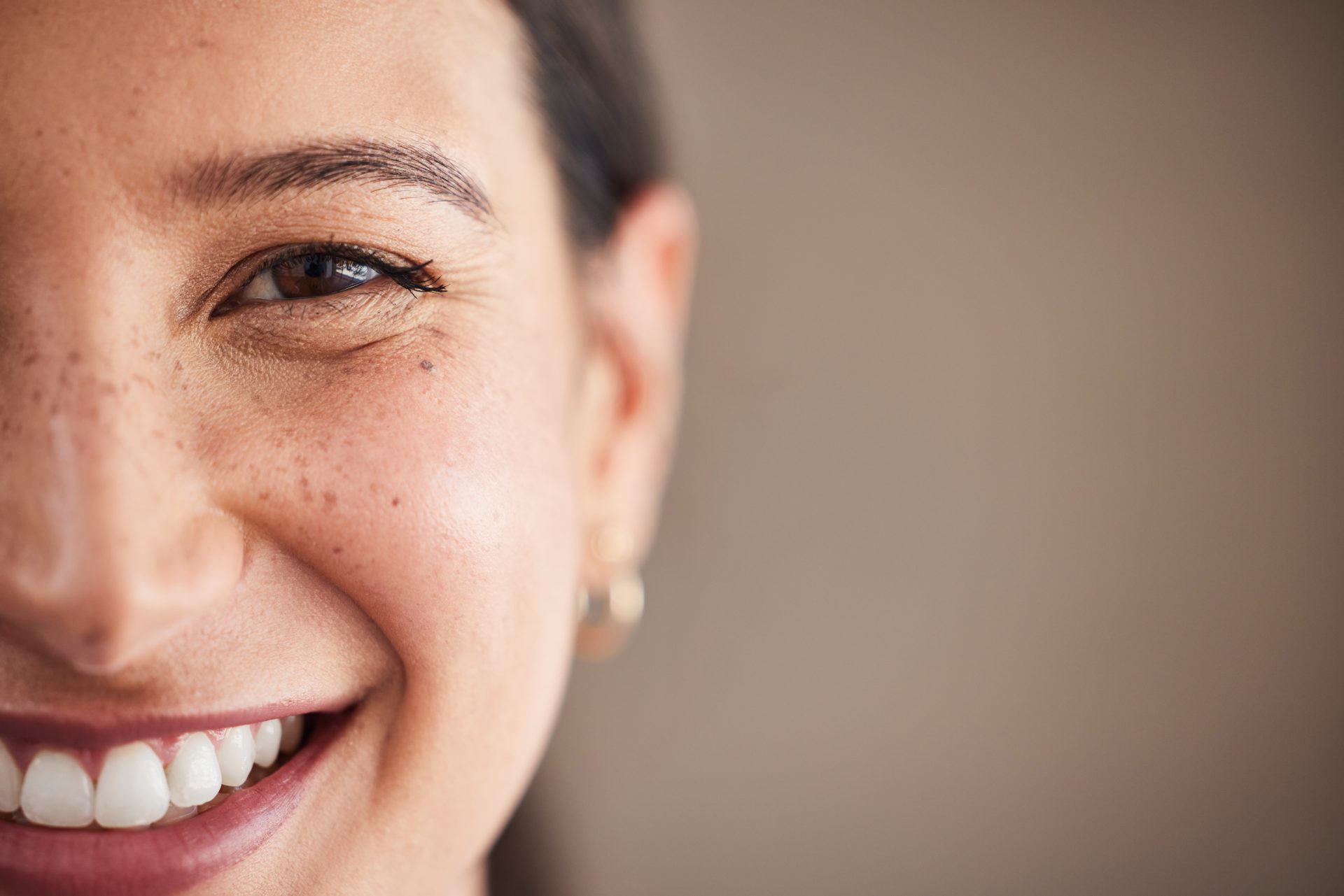 Face of beautiful mixed race woman smiling with white teeth. Portrait of a woman's face with brown eyes and freckles posing with copy-space. Dental health and oral hygiene