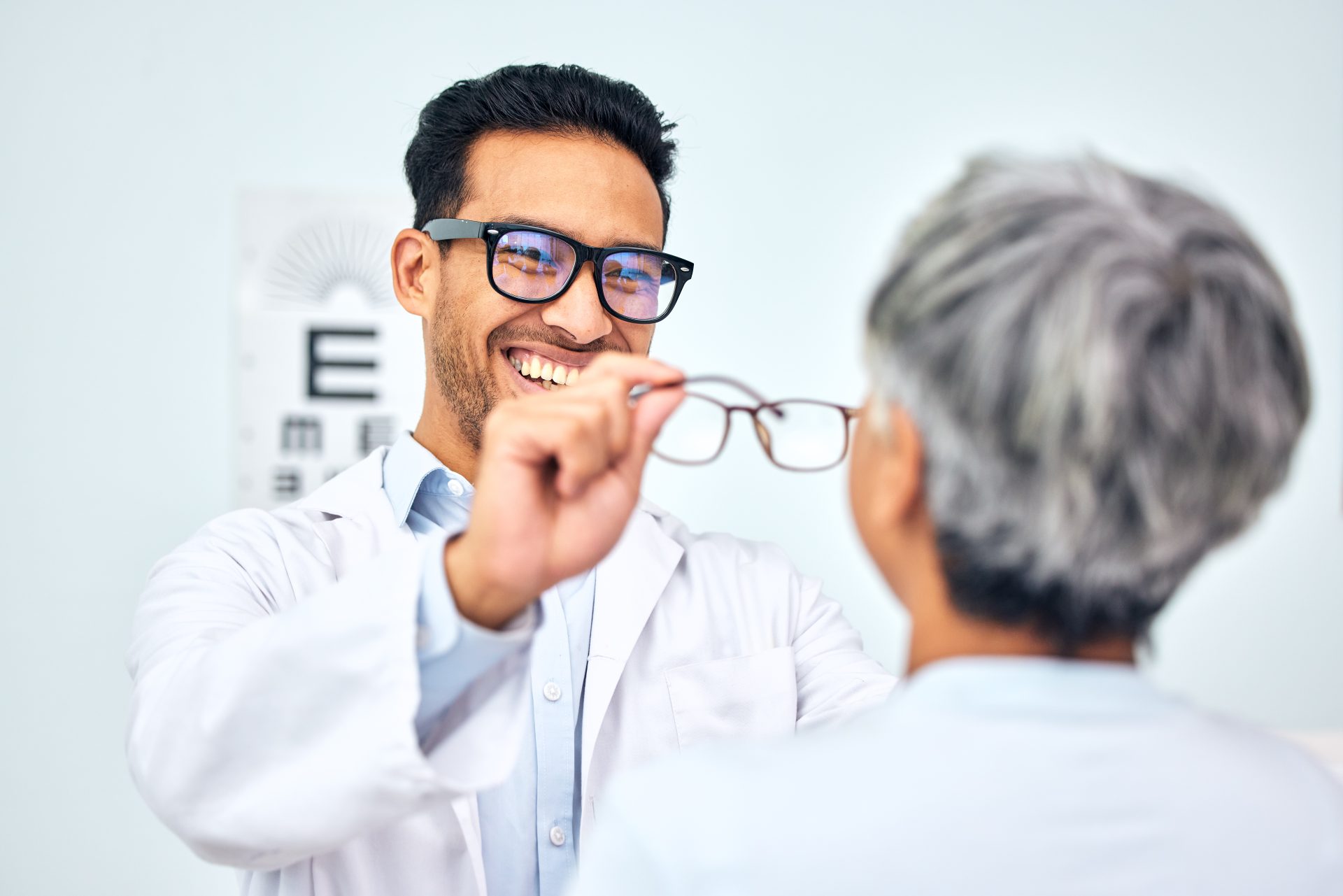 Glasses, optometrist and client with appointment, vision and consultation with diagnosis, smile and help. Office, employee and senior woman with eyewear, doctor and healthcare with wellness and frame